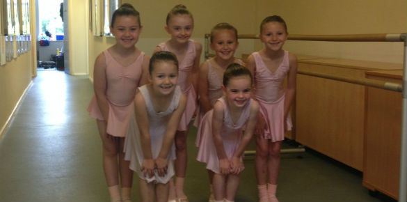Six young ballet dancers standing together as they wait for their exam.